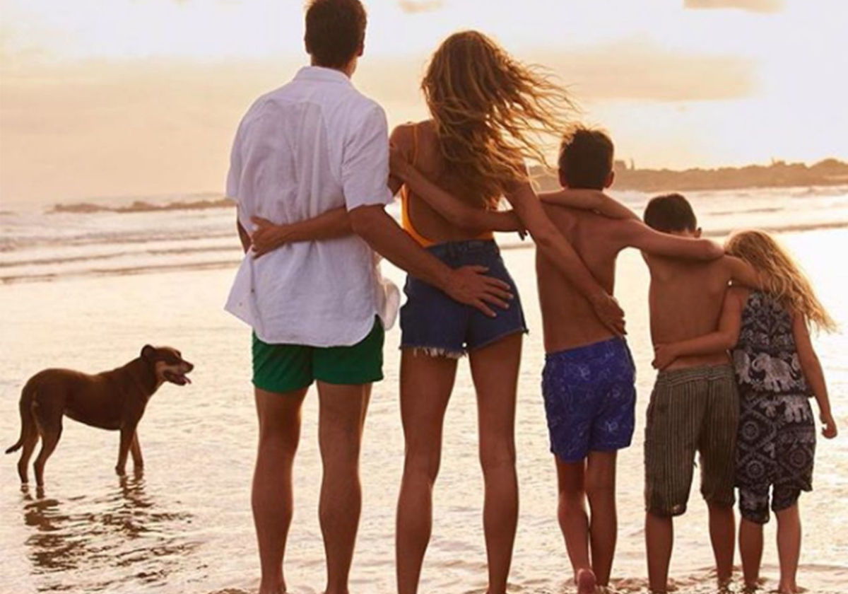 Matrimonio con sus tres hijos y el perro miran al mar